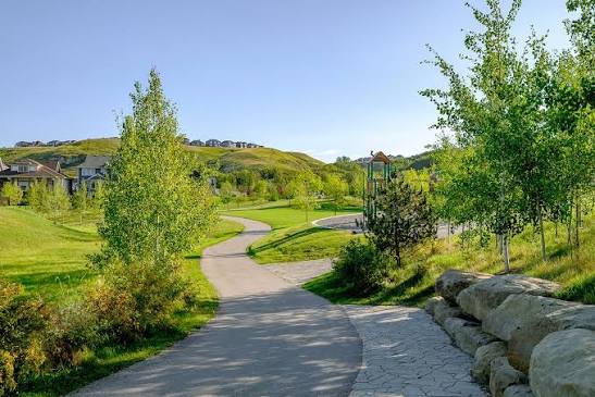 A paved pathway winding through the green space in McKenzie Towne, Calgary